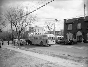 Passengers stand around a J.G. Brill trolley coach (electric bus) at the corner of 16th and Boulder Streets. The Olinger Mortuary can be seen nearby. Image courtesy Stephen H. Hart Library & Research Center, History Colorado.